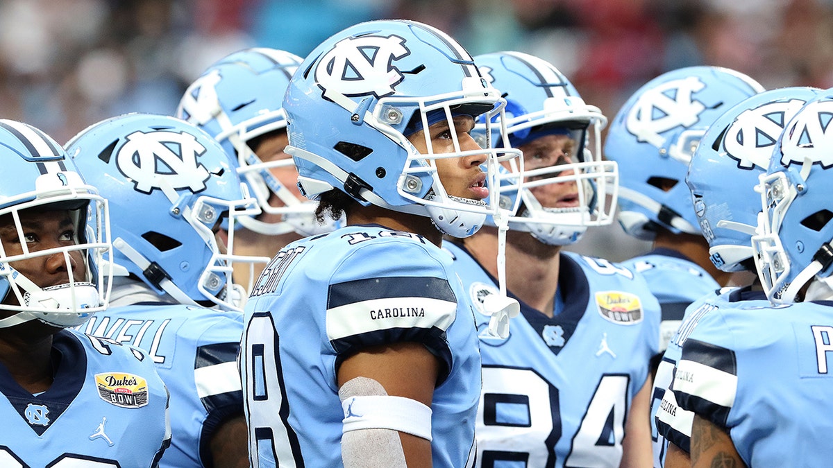 UNC football players stand and look