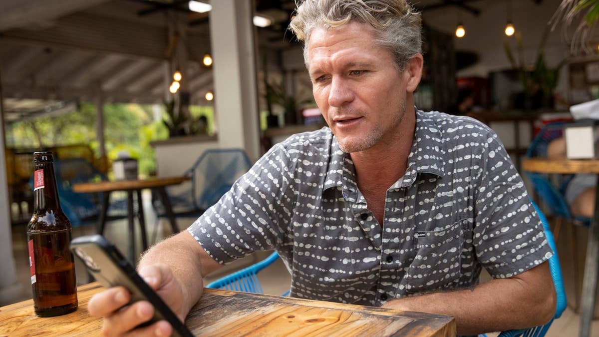 Teal Oceans Akerson looks at his phone while seated at a cafe table