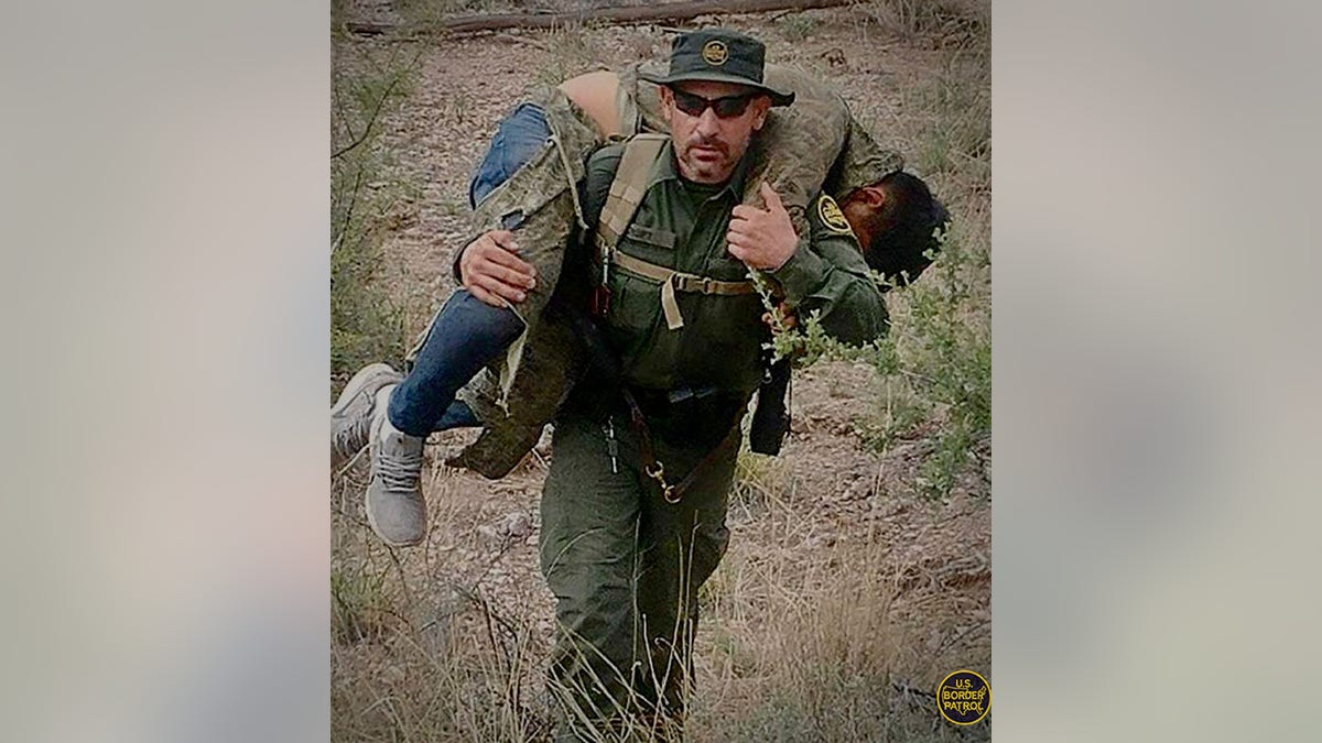 Border agent carrying injured juvenile migrant