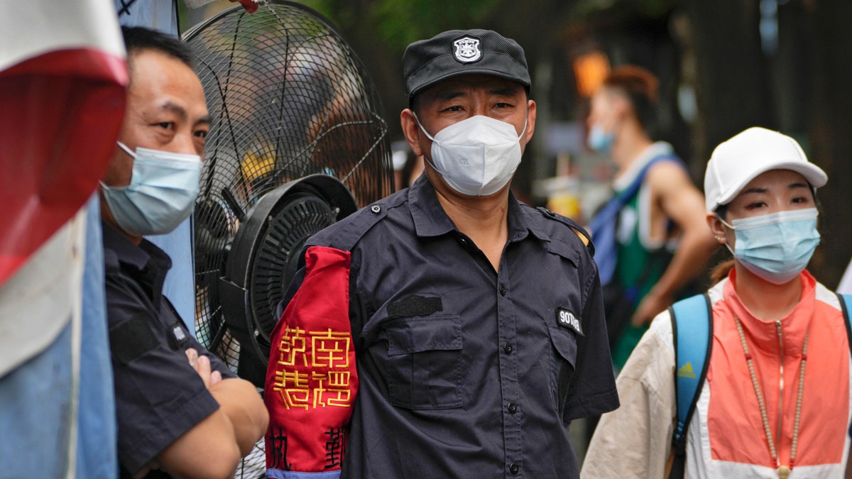 Chinese security guard stands with citizens