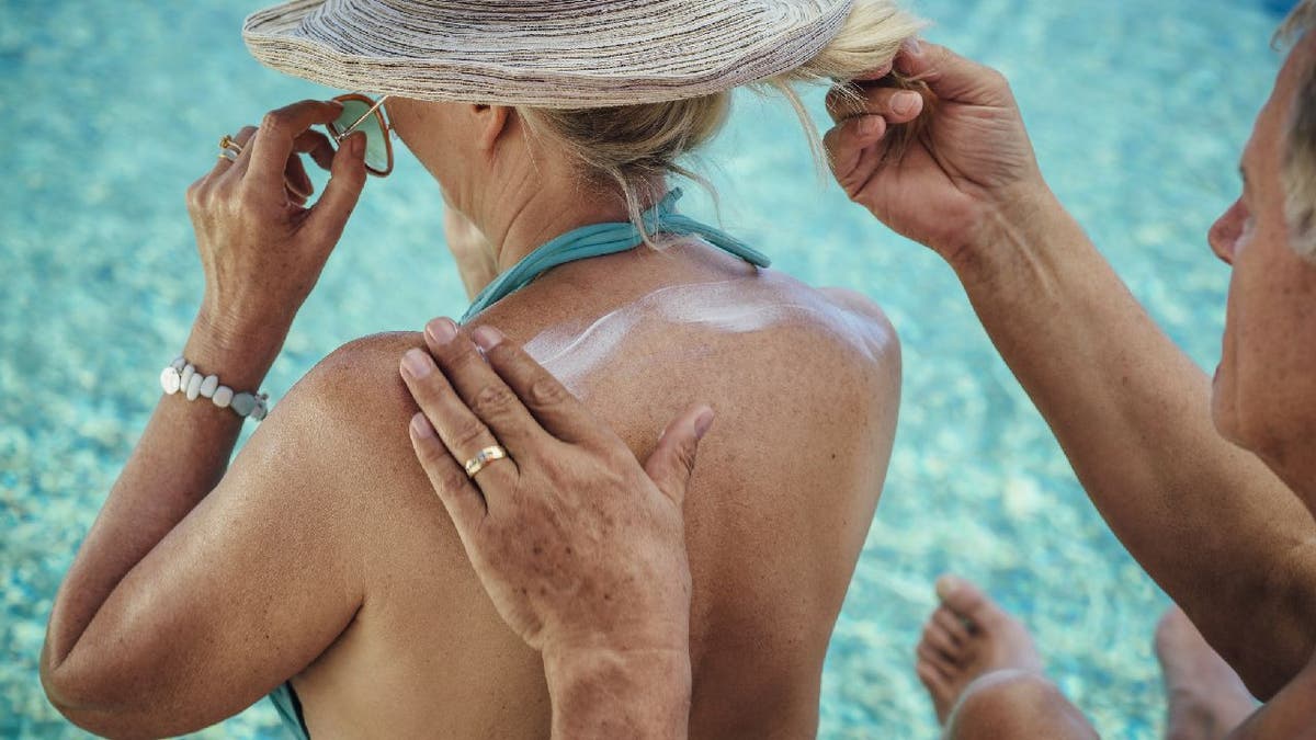 Man applies sunscreen on woman's back