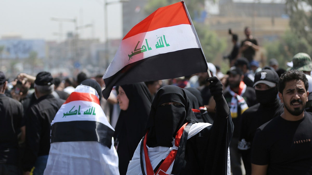 Protest in Baghdad with people flying the Iraqi flag