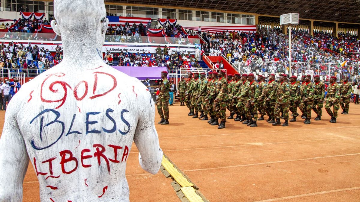 Liberia bicentennial parade includes a man in white with "God bless Liberia" on his back