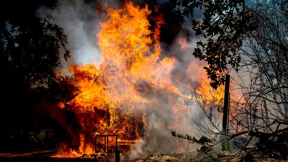 Fire and smoke billows from a home consumed by wildfire