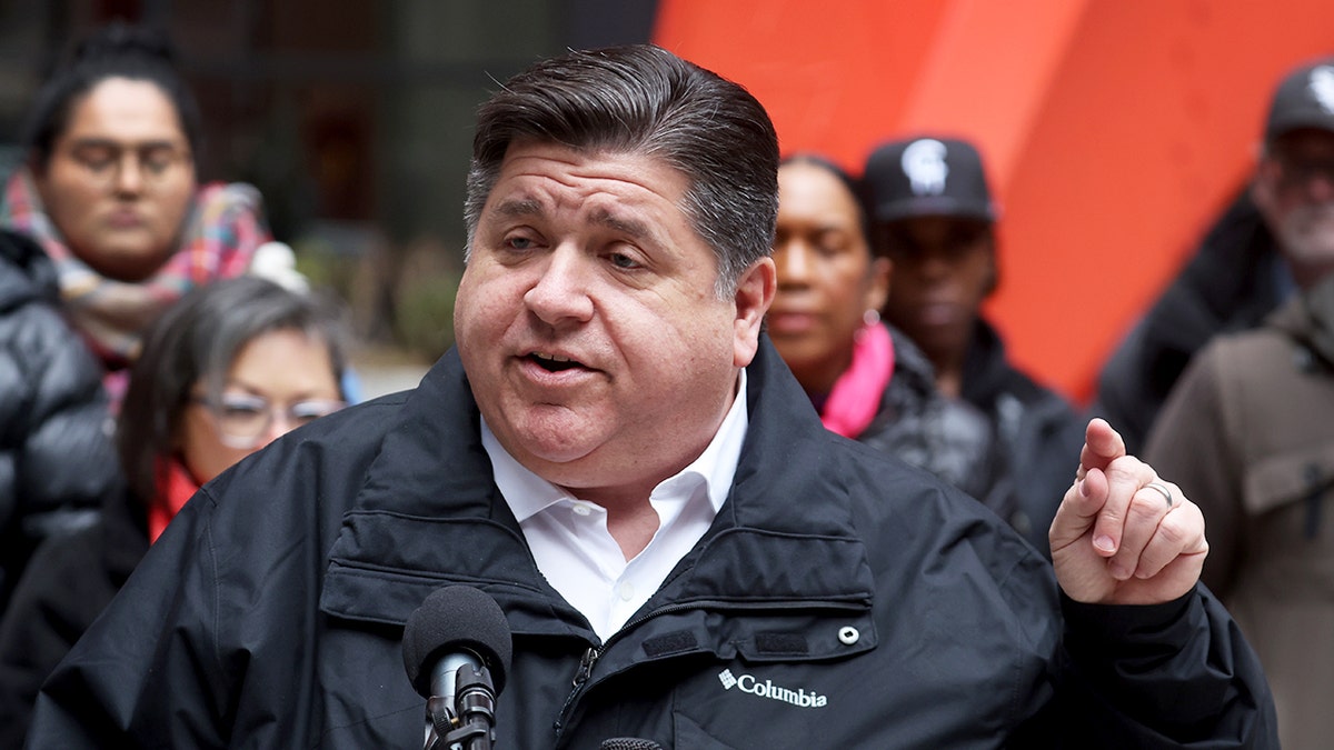 Gov. JB Pritzker in a raincoat speaking to audience