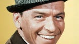 The popular American singer Frank Sinatra is shown here in this closeup photo smiling. His nicknames include "Ol' Blue Eyes" and "Chairman of the Board".
