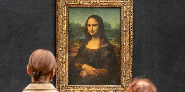 Visitors observe the painting 'La Joconde' The Mona Lisa by Italian artist Leonardo da Vinci on display in a gallery at Louvre on May 19, 2021 in Paris.