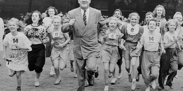 Big Jim Thorpe, famed American athlete and former U.S. Olympic great, center, sets a fast pace for some girls during a