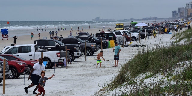 Beach-goers are seen near their cars at Daytona Beach in May 2020 as sections of Volusia County beaches reopened amidst the COVID-19 pandemic.