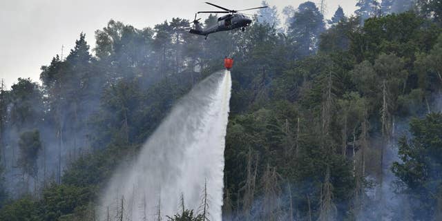 A helicopter cannons water as fires burn in the area of ​​National Park near Frensko, Czech Republic and České Svycarsko, Czech Switzerland.