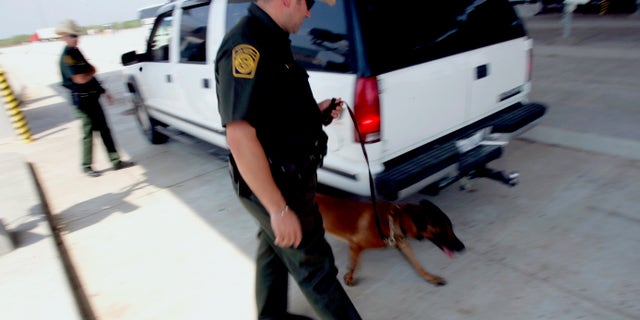 U.S. Border Patrol agents check a car's occupants and use a dog at a checkpoint coming into the U.S. outside Laredo, Texas.