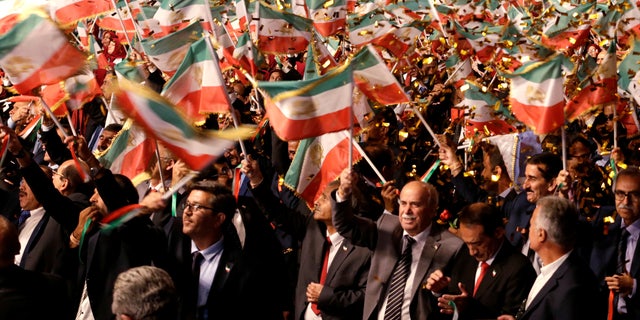 People wave flags during an event at the Ashraf-3 camp, home of the People's Mojahideen Organization of Iran (MEK), in Manza, Albania, on July 13, 2019.