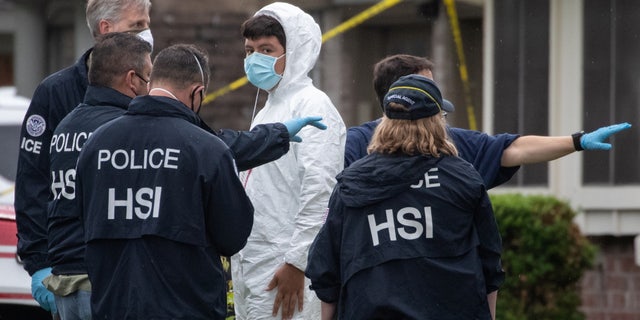 Homeland Security Investigations (HSI) personnel surround a man as he exits from a residence in southwest Houston, Texas, U.S., April 30, 2021. Police responding to reports of a kidnapping said they had found more than 90 people crammed into a two-story suburban Houston home and suspected it was being used in a human smuggling operation.  