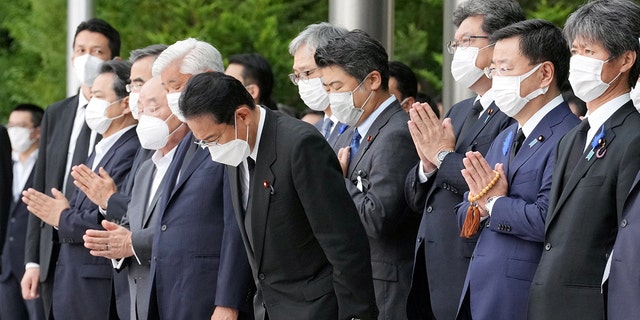 Japan's Prime Minister Fumio Kishida, officials and employees offer prayers towards a hearse carrying the body of late former Japanese Prime Minister Shinzo Abe, in Tokyo, Japan, July 12, 2022. 