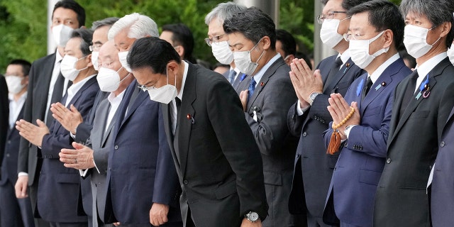 Japan's Prime Minister Fumio Kishida, officials and employees offer prayers towards a hearse carrying the body of late former Japanese Prime Minister Shinzo Abe, in Tokyo, Japan, July 12, 2022.