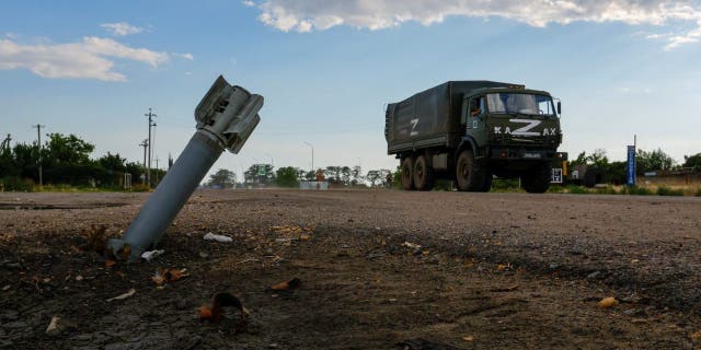 A Russian military truck drives past an unexploded munition during Ukraine-Russia conflict in the Russia-controlled village of Chornobaivka, Ukraine, July 26, 2022.