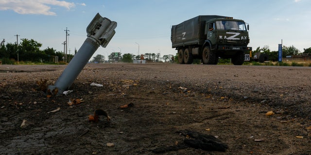 Een Russische militaire vrachtwagen rijdt langs een niet-ontplofte munitie tijdens het conflict tussen Oekraïne en Rusland in het door Rusland gecontroleerde dorp Chornobaivka, Oekraïne, 26 juli 2022.