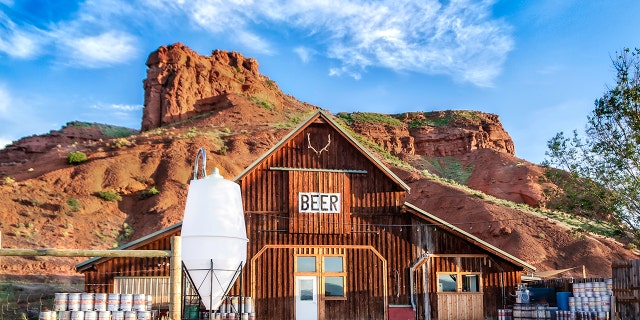 The Ten Sleep Brewery barn is shown in front of the red cliffs of Signal Butte, in the town of Ten Sleep, Wyoming.