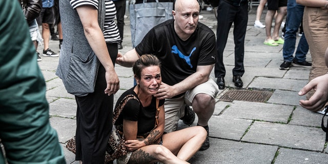 People help a woman in front of the Fields shopping center in Copenhagen, Denmark, Sunday, July 3, 2022. 