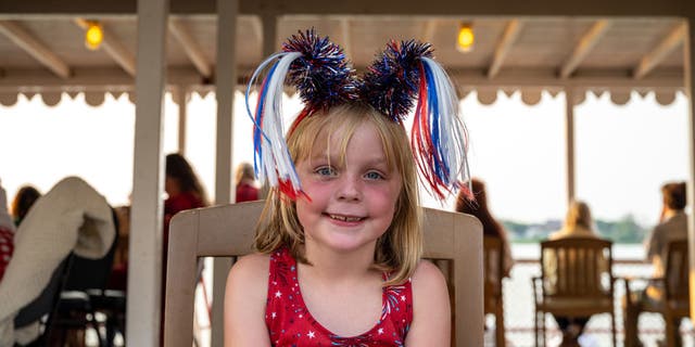 A young person wearing U.S. flag attire smiles during on deck of the Belle of Louisville, a historic steamboat, during the Fourth of July Fireworks Cruise on July 4, 2021, in Louisville, Kentucky.