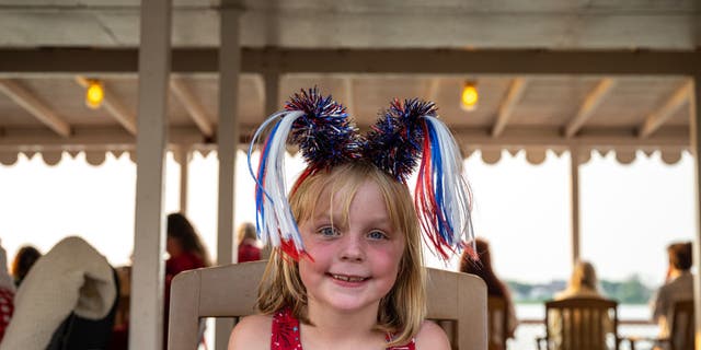 Un jeune homme portant un vaisseau amiral américain rit sur le pont de la Belle of Louisville, un bateau à vapeur historique, lors de la croisière Fireworks du 4 juillet 2021, à Louisville, Kentucky.