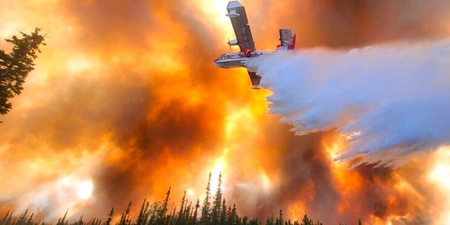 In this photo provided by Eric Kiehn, Northwest Incident Management Team 10, Alaska Division of Forestry, a fixed-wing aircraft drops water on the Clear Fire near Anderson, Alaska, July 6, 2022. 