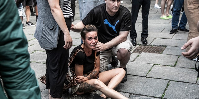 People help a woman in front of the Fields shopping center in Copenhagen, Denmark, Sunday, July 3, 2022.P)