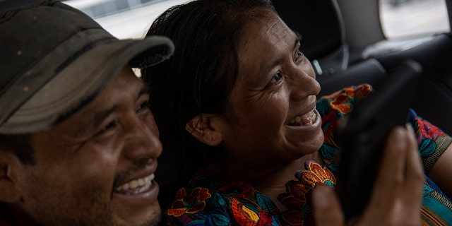 Mynor Cardona and Ufemia Tomas, parents of Yenifer Yulisa Cardona Tomás, smile as they talk with her through a call to the hospital where she is being treated in Guatemala City, Monday, July 4, 2022.