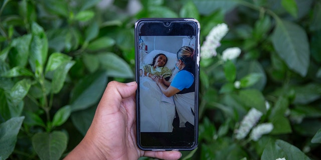Mynor Cardona shows a photo on his cellphone of her daughter, Yenifer Yulisa Cardona Tomás, at the hospital while receiving a visit, in Guatemala City, Monday, July 4, 2022. 