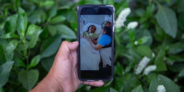 Mynor Cardona shows a photo on his cellphone of her daughter, Yenifer Yulisa Cardona Tomás, at the hospital while receiving a visit, in Guatemala City, Monday, July 4, 2022.