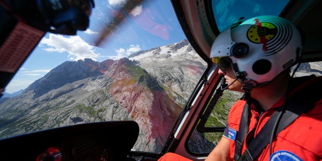 A rescuer pilots a helicopter to conduct searches for the victims of the Punta Rocca glacier avalanche in Canazei, in the Italian Alps in northern Italy, on Tuesday, July 5. 