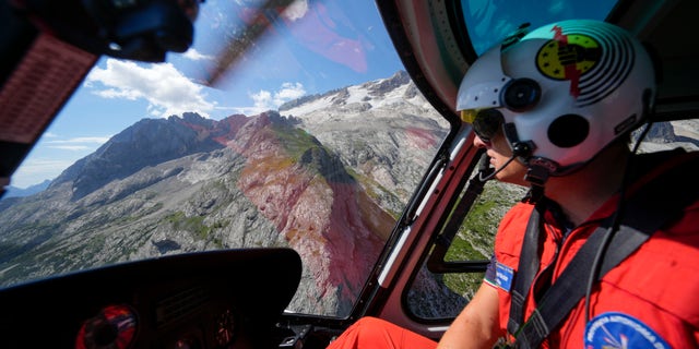 A rescuer pilots a helicopter to conduct searches for the victims of the Punta Rocca glacier avalanche in Canazei, in the Italian Alps in northern Italy, on Tuesday, July 5.