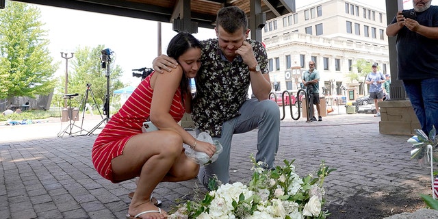 Brooke and Matt Strauss, who were married on Sunday, pause after leaving their wedding bouquets in downtown Highland Park, Ill., a Chicago suburb, near the scene of Monday's mass shooting, on Tuesday, July 5, 2022.