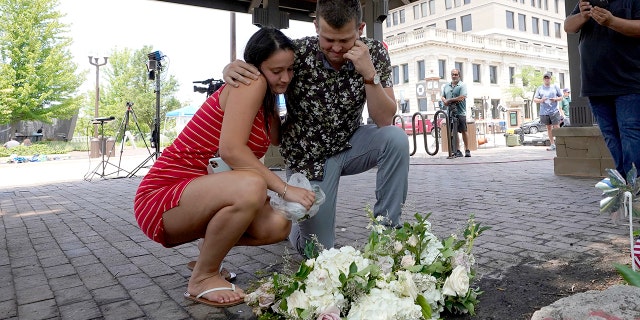 Brooke and Matt Strauss, who were married Sunday, pause after leaving their wedding bouquets in downtown Highland Park, Ill., a Chicago suburb, near the scene of Monday's mass shooting, Tuesday, July 5, 2022.