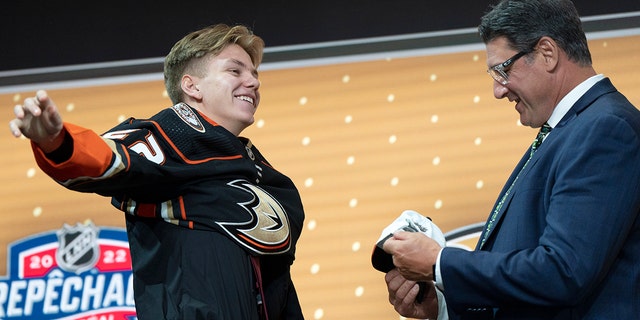 Pavel Mintyukov puts on an Anaheim Ducks jersey after being selected in the NHL Hockey Draft in Montreal on Thursday, July 7, 2022. 