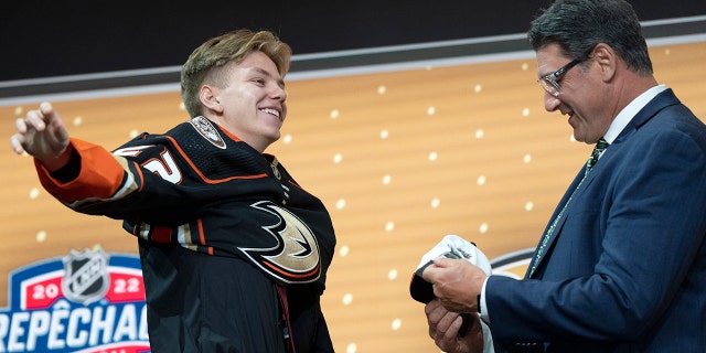 Pavel Mintyukov puts on an Anaheim Ducks jersey after being selected in the NHL Hockey Draft in Montreal on Thursday, July 7, 2022.