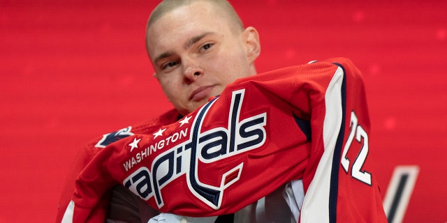 Ivan Miroshnichenko puts on a Washington Capitals jersey after being selected in the first round of the NHL Hockey Draft in Montreal on Thursday, July 7, 2022.
