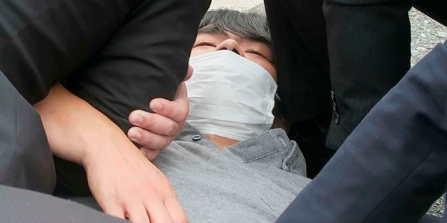 In this image from a video, Tetsuya Yamagami is detained near the site of gunshots in Nara, western Japan Friday, July 8, 2022. Nara prefectural police confirmed the arrest of Yamagami, 41, on suspicion of attempted murder.