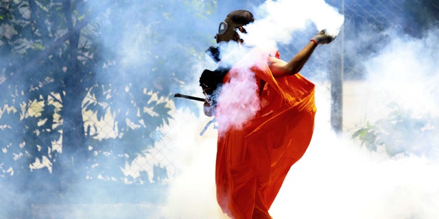 A man throws back a tear gas shell after it was fired by police to disperse the protesters in Colombo, Sri Lanka, Saturday, July 9, 2022. Sri Lankan protesters demanding that President Gotabaya Rajapaksa resign forced their way into his official residence on Saturday, a local television report said, as thousands of people took to the streets in the capital decrying the island nation's worst economic crisis in recent memory. (AP Photo/Amitha Thennakoon)