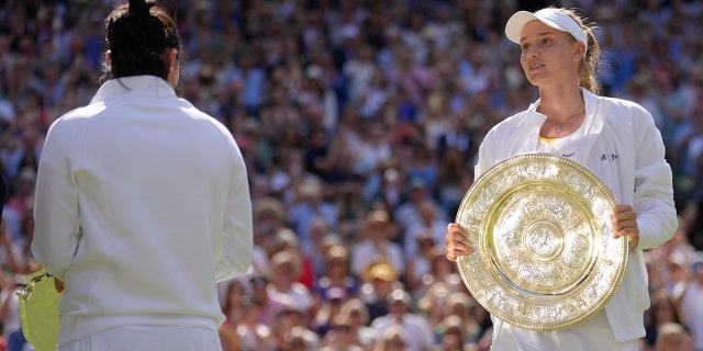 Kazakhstan's Elena Rybakina celebrates with the trophy after beating Tunisia's Ons Jabeur, left, to win the women's singles championship at Wimbledon in London Saturday, July 9, 2022. 