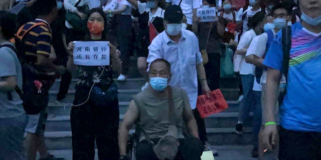 In this photo, released by Yang on Sunday, July 10, 2022, people are raising the flag of protest at a branch of the Central Bank of China in Zhengzhou, Henan Province, central China. Protesters gathered in front of the People's Bank of China building in Zhengzhou before dawn on Sunday. In the video shot in the early morning darkness, you can see a police car with blinking lights. Police closed the street and began to gather on the other side by 8 am, Zhang said.