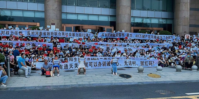In this photo released by Yang on Sunday, July 10, 2022, people hold banners and chant slogans during a protest at the entrance to a Chinese central bank branch in Zhengzhou, central China's Henan province.  A large crowd of angry Chinese bank depositors confronted police on Sunday, some allegedly injured as they were brutally taken away, in a case that attracted attention due to previous attempts to use a COVID-19 tracking app to prevent them from mobilizing.  (Photo AP / Yang)