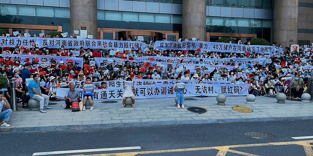 In this photo released by Yang on Sunday, July 10, 2022, people hold banners and chant slogans during a protest at the entrance to a Chinese central bank branch in Zhengzhou, central China's Henan province.  A large crowd of angry Chinese bank depositors confronted police on Sunday, some allegedly injured as they were brutally taken away, in a case that attracted attention due to previous attempts to use a COVID-19 tracking app to prevent them from mobilizing.  (Photo AP / Yang)