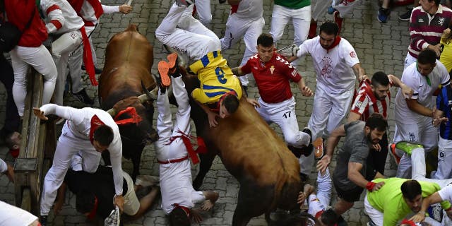 Runners fall and get hit by fighting bulls during the running of the bulls event at the Festival of San Fermin in Pamplona, Spain, Monday, July 11, 2022.