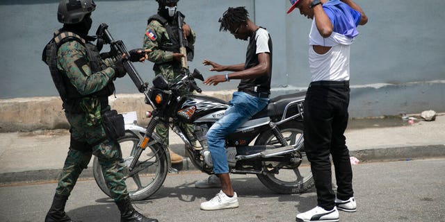 Armed forces check two men who were riding a motorcycle for weapons at the state office area in Port-au-Prince, Haiti on Monday, July 11, 2022. 