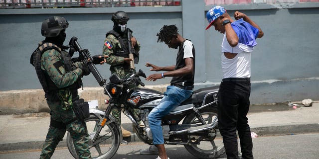 Armed forces check two men who were riding a motorcycle for weapons at the state office area in Port-au-Prince, Haiti on Monday, July 11, 2022. 