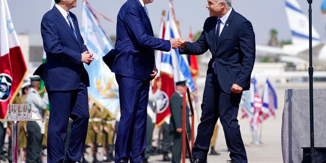 President Joe Biden is greeted by Israeli Prime Minister Yair Lapid, right and President Isaac Herzog, left, as they participate in an arrival ceremony after Biden arrived at Ben Gurion Airport, Wednesday, July 13, 2022, in Tel Aviv. (AP Photo/Evan Vucci)