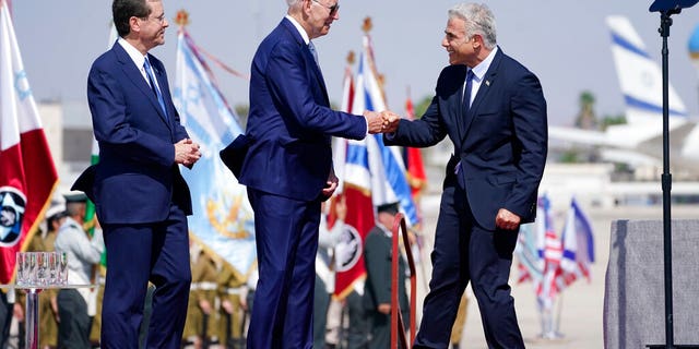 President Joe Biden is greeted by Israeli Prime Minister Yair Lapid, right and President Isaac Herzog, left, as they participate in an arrival ceremony after Biden arrived at Ben Gurion Airport, Wednesday, July 13, 2022, in Tel Aviv. (AP Photo/Evan Vucci)