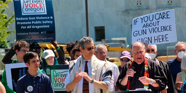 Rev. Mark Knutson, right, chief petitioner of a gun initiative, speaks at a rally, joined by Rabbi Michael Cahana, center, outside the Oregon State Capitol in Salem before signatures are delivered to Oregon elections officials to get the proposal on the ballot on July 8, 2022.