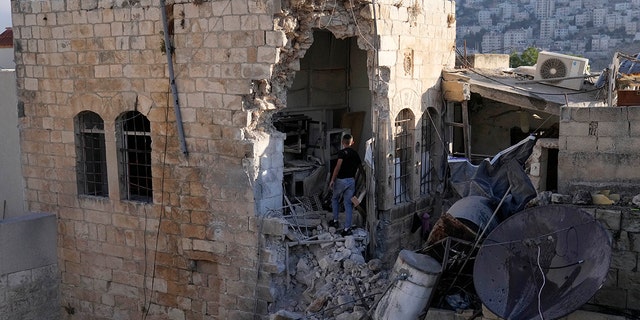 A Palestinian boy inspects the damage to a house after Palestinian gunmen were killed in an early morning Israeli military raid in the Old City of Nablus in the West Bank, Sunday, July 24, 2022. 